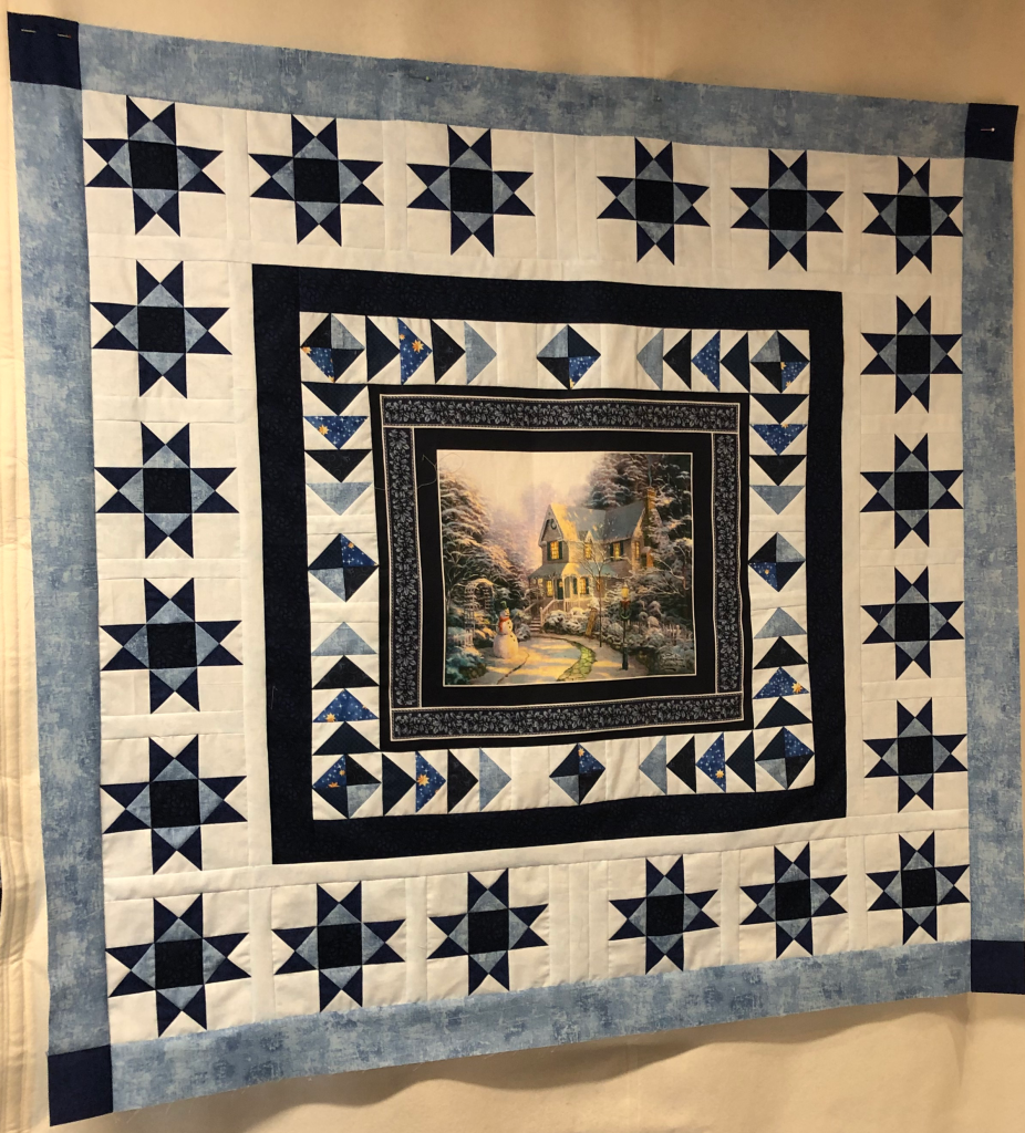 Weihnachtlicher Wand Quilt mit einem Panel (schneebedecktes Haus in einem Park und Schneemann davor in der Mitte, Einem Rand aus Flying Geese und einem weiteren Rand aus Sternen